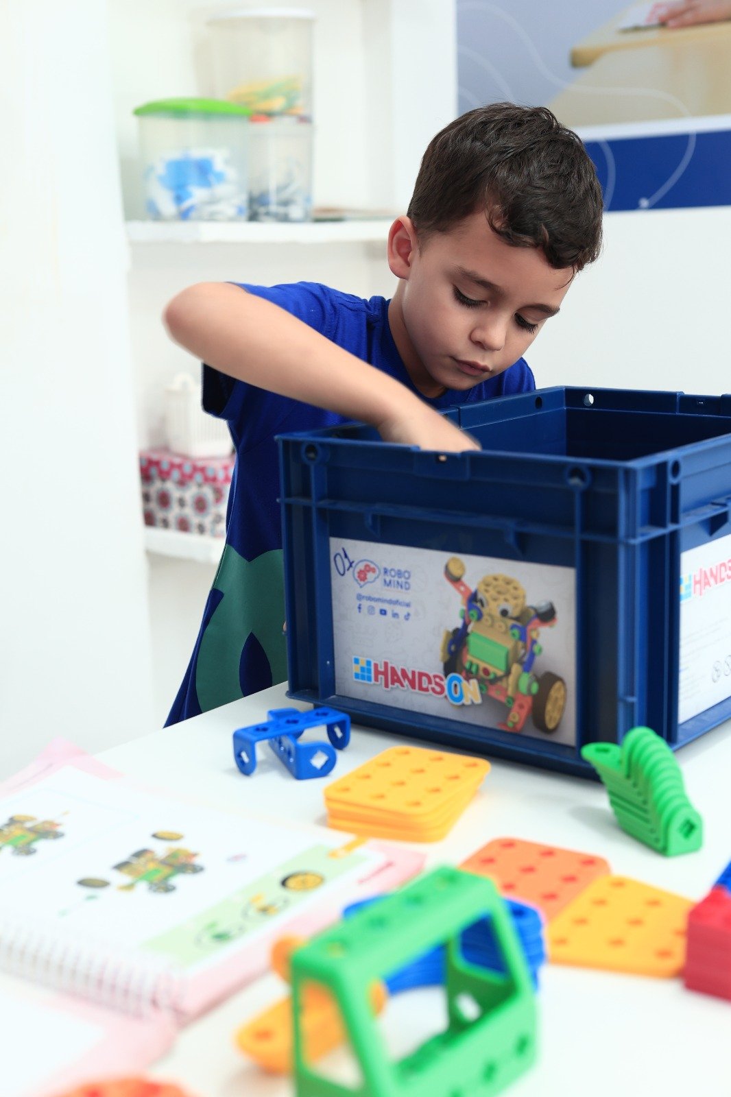 Menino colocando peças de robótica em caixa azul