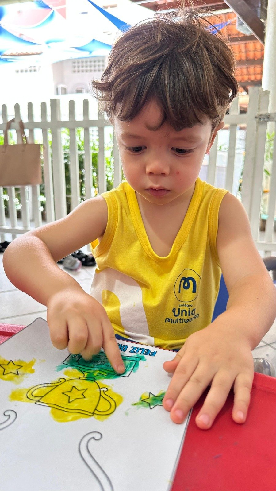 Menino pintando troféu dourado com camisa do UNIQ Multiverso