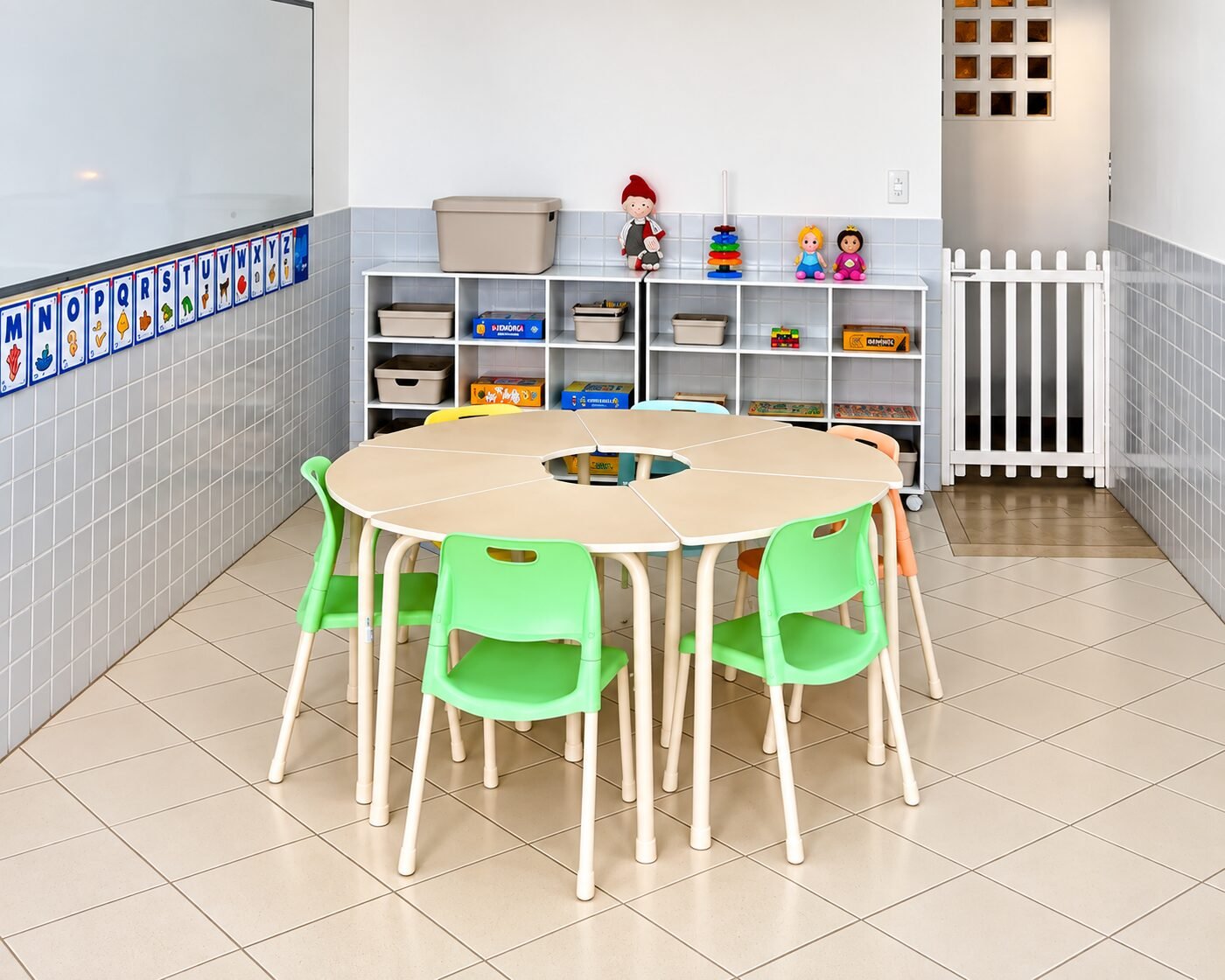 Sala de aula da Educação Infantil com mesas redondas e cadeiras verdes